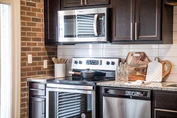 a kitchen with stainless steel appliances and black cabinets at The Foundry, South Bend, IN 46617